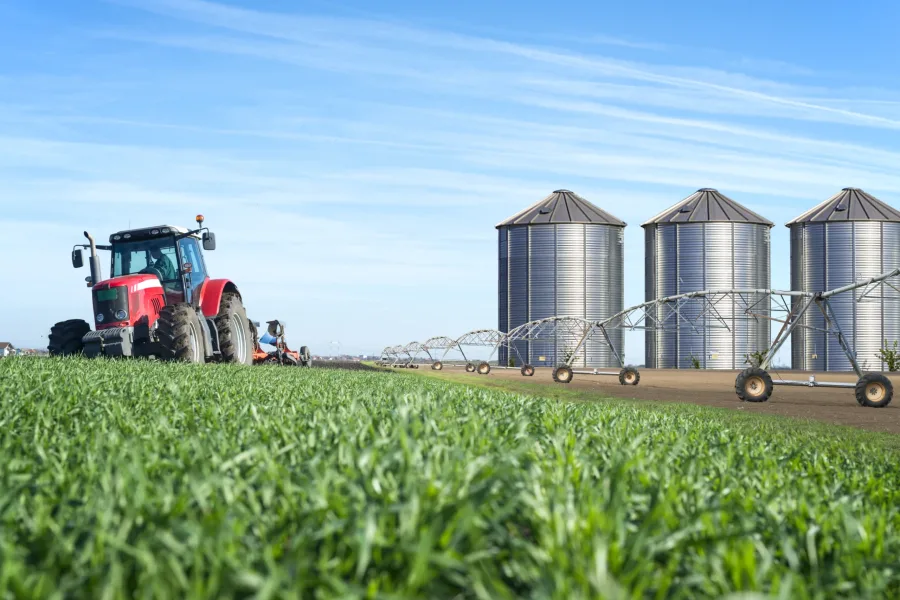 Agriculture and food production concept with tractor machine silos and irrigation system.