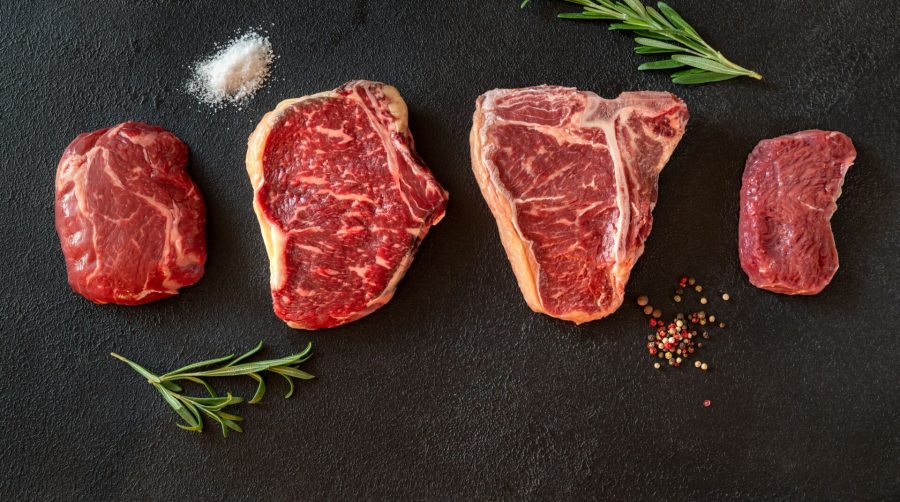 Variety of beef steaks on dark background