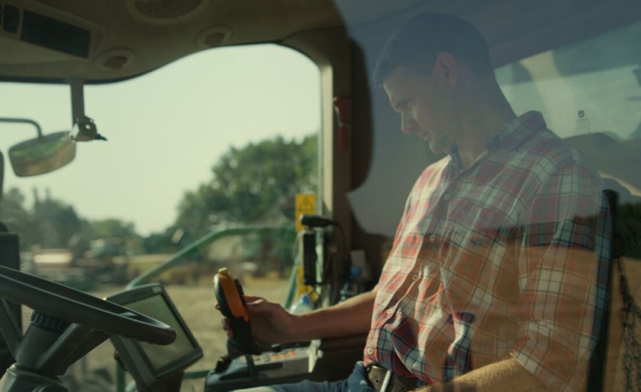 Driver farmer working machine automation in cockpit. Focused man control harvest system at countryside. Agricultural professional operator checking harvester automation. Agritech industry concept.